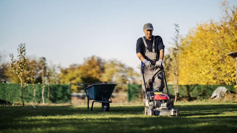 A man in overalls mowing his lawn
