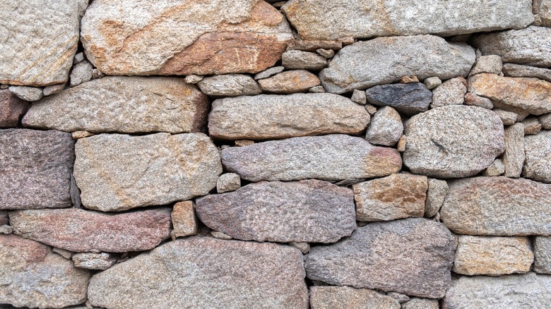 A close-up photo of granite stones building up a retaining wall