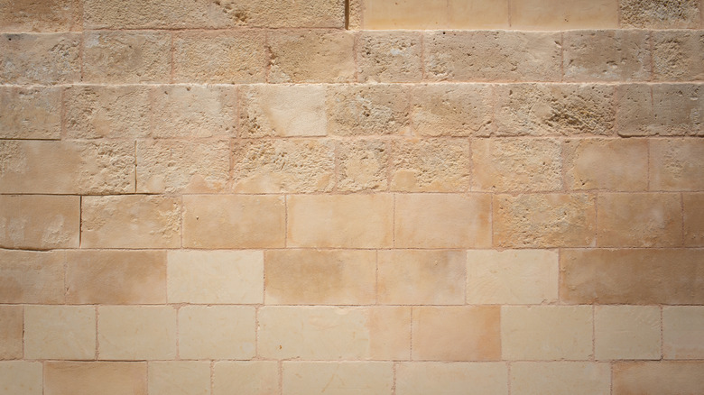 A close-up photo shows the texture of a wall made from beige limestone