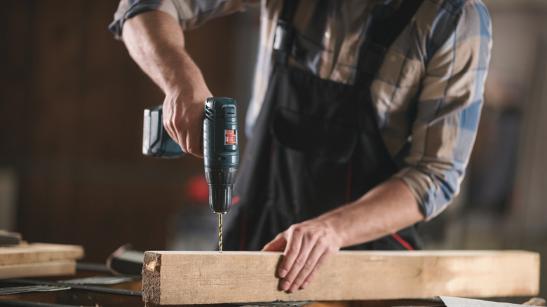 Worker drilling through wood