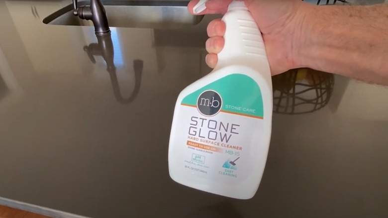 Person holding a spray bottle of MB-15 quartz cleaner