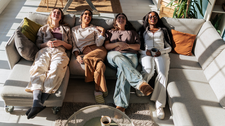 For women siting comfortably on large sectional sofa in living room.