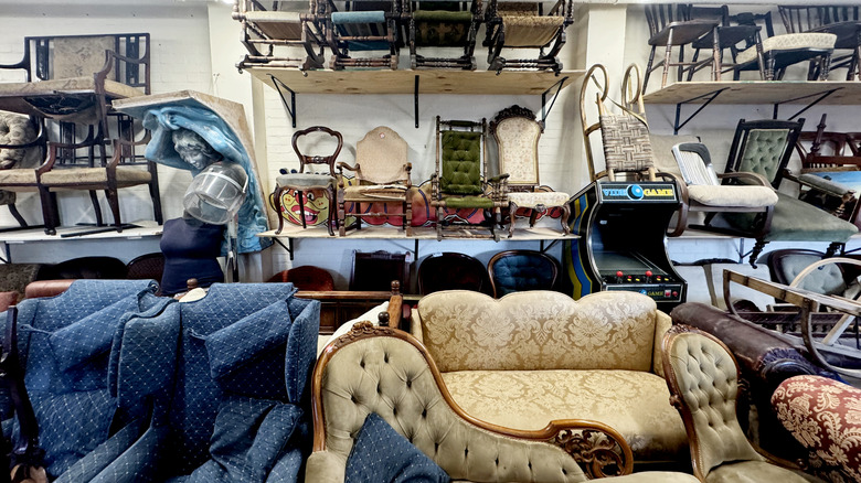 Thrift store furniture section with sofas, chairs, and other items