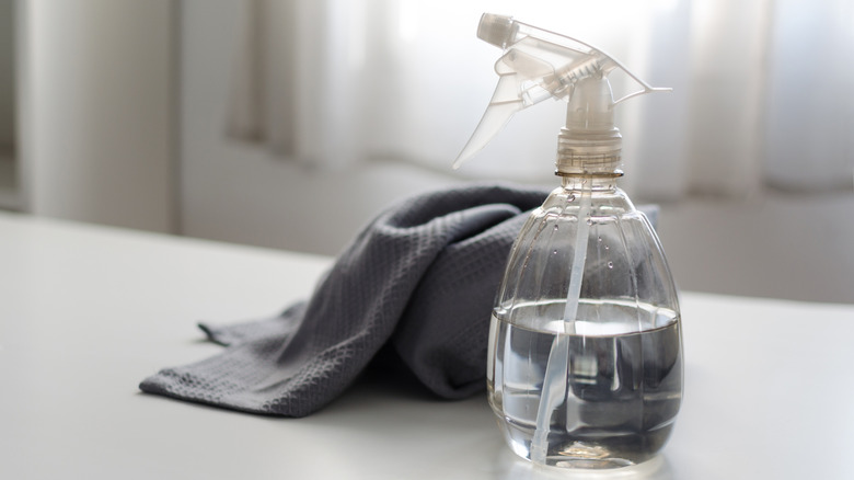 Spray bottle next to gray cloth on white countertop