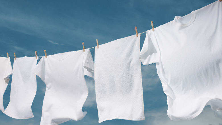 White clothes and towels hanging on a washing line beneath a blue sky