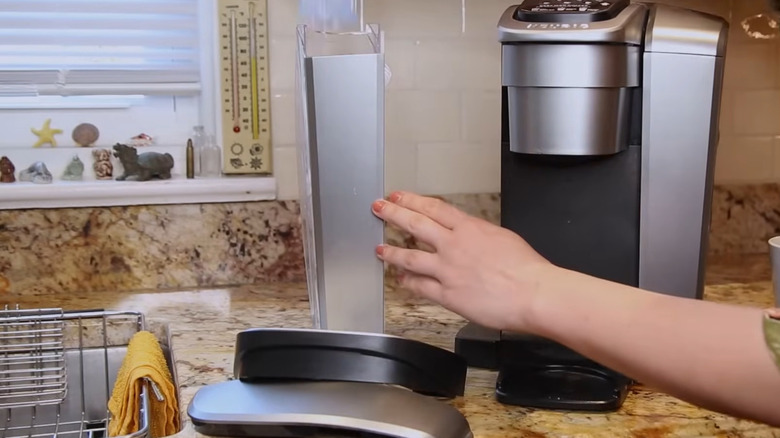 Person removing all of the parts of a Keurig to wash them