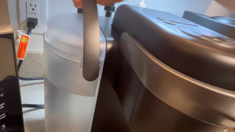 Person lifting the water tank off of a Keurig machine