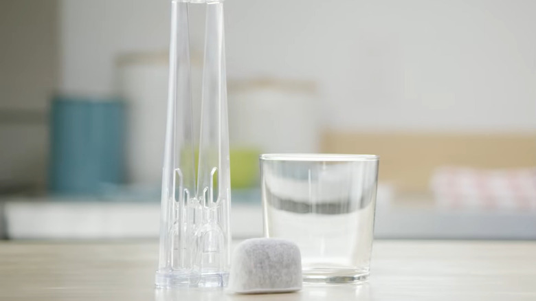 A Keurig filter, the filter holder, and a cup sitting on a counter