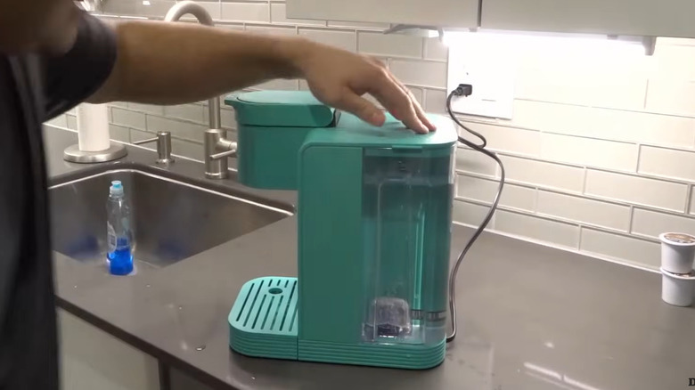 Person putting a refilled water reservoir on a Keurig machine