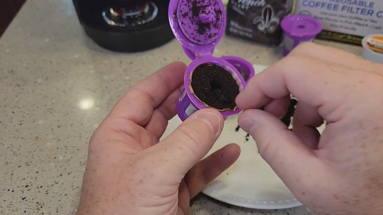 Person emptying out a reusable K-cup with old coffee grounds in it