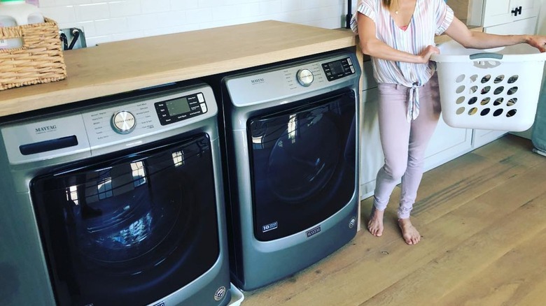Woman standing with a laundry basket near Maytag washer and dryer