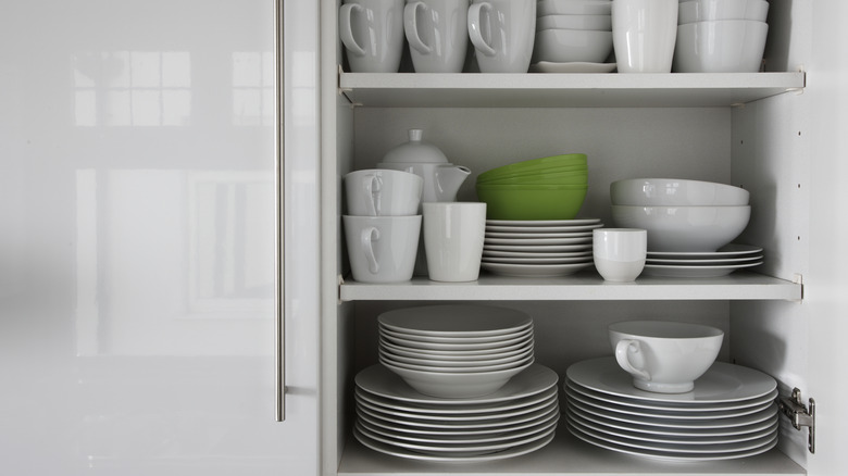 White plates are stacked in a cupboard