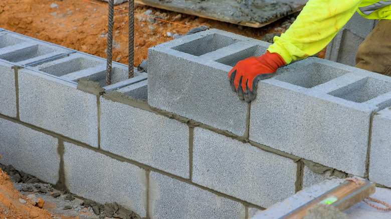 A man building a retaining wall from concrete blocks.