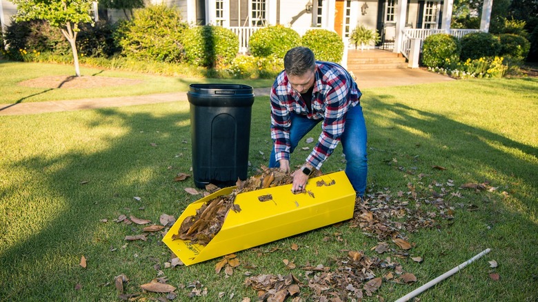 A man lifting up the Leaf Easy Leaf Scoop in yellow full of leaves