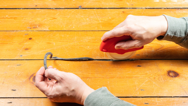 Person filling in gaps in old wood floorboards
