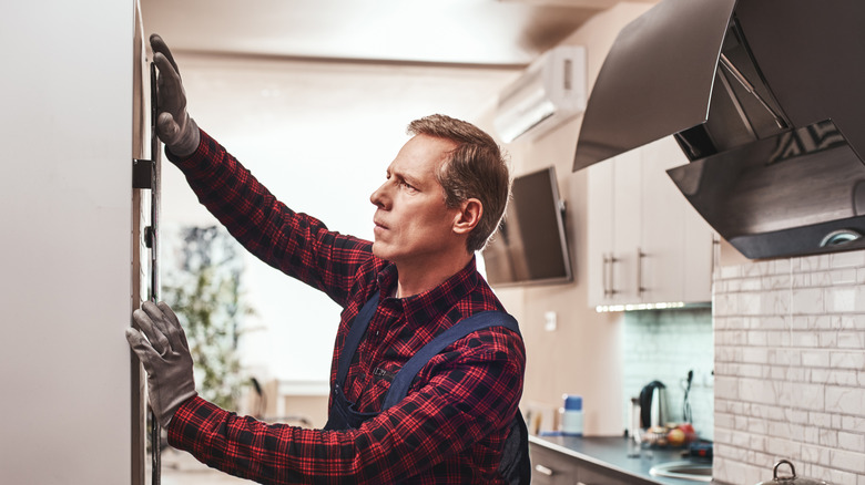 Handyman installing a white refrigerator in a kitchen