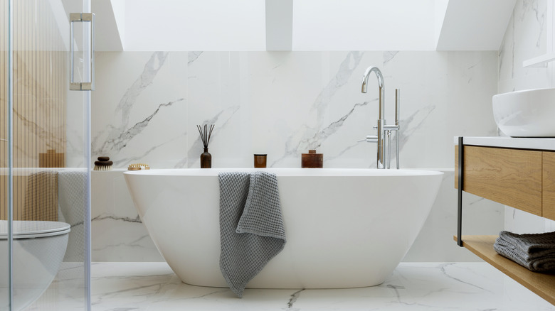 White free standing bathtub in a bathroom drenched in marble