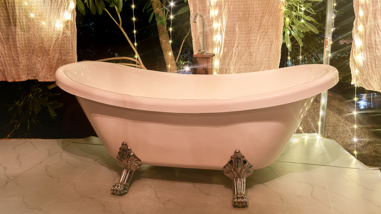 Bathtub outdoors in a backyard with curtains and fairylights