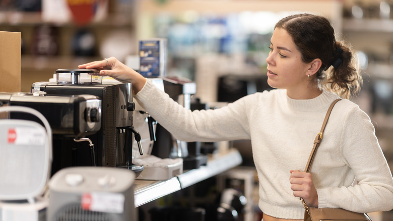 A woman in an appliance store looking at a coffee maker.