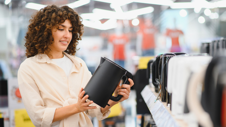 A customer comparing electric kettles in a home appliance store