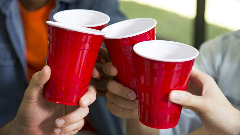 People holding red plastic cups