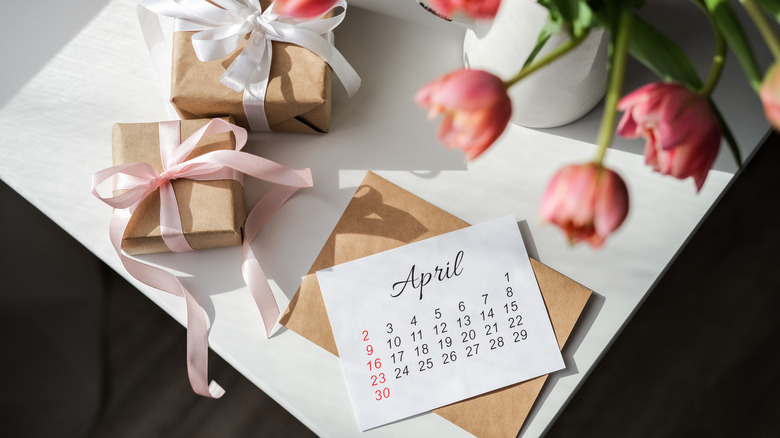 April calendar with gift boxes and a tulip bouquet on table