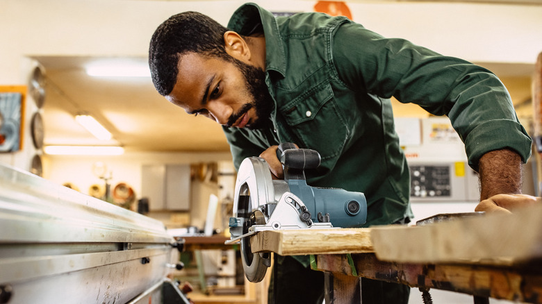A man cuts a piece of lumber with a circular saw