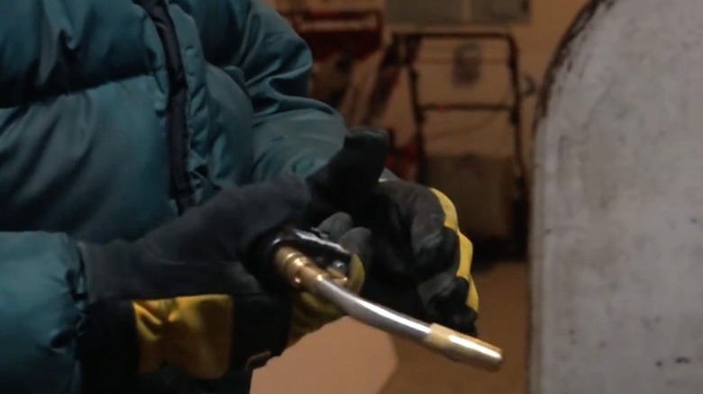 Man in gloves and protective clothing handling butane torch