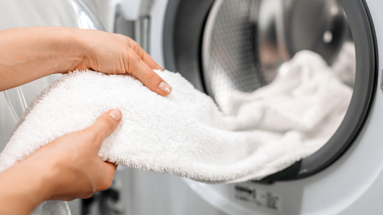 Hands pulling dry, fluffy, white towel from dryer