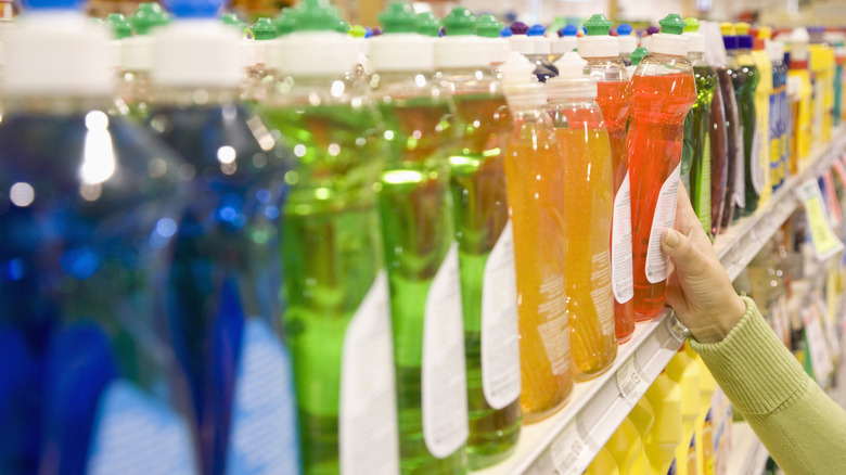A person grabbing dish soap from a shelf in a store