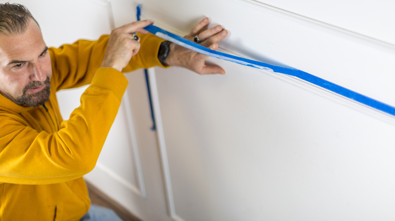 Man removing blue painter's tape from wall