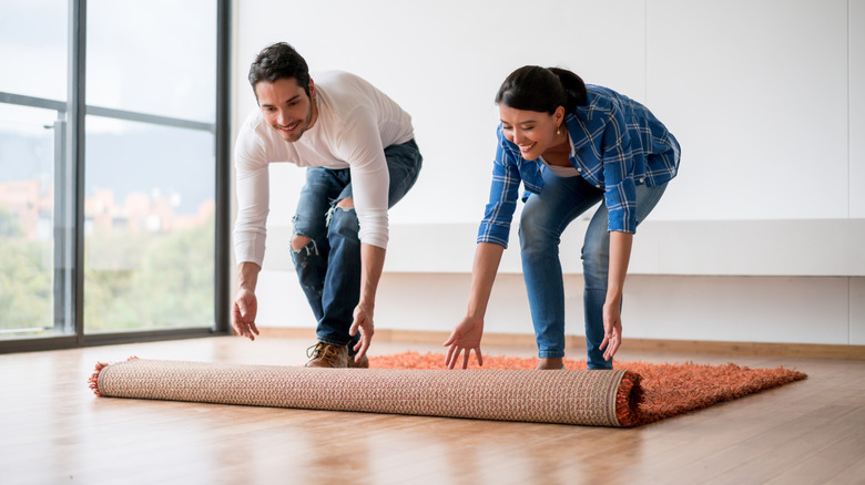 Couple unrolling a rug