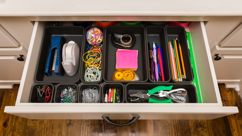 Tidy drawer with office supplies in black organizers.