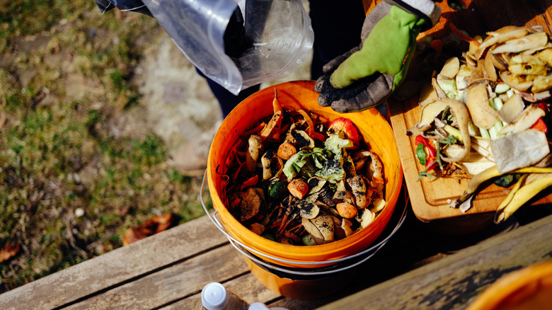 Someone preparing a bokashi compost bucket with lots of food scraps.