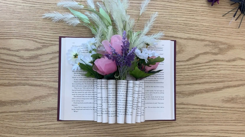 A hardcover book turned into a vase for faux flowers