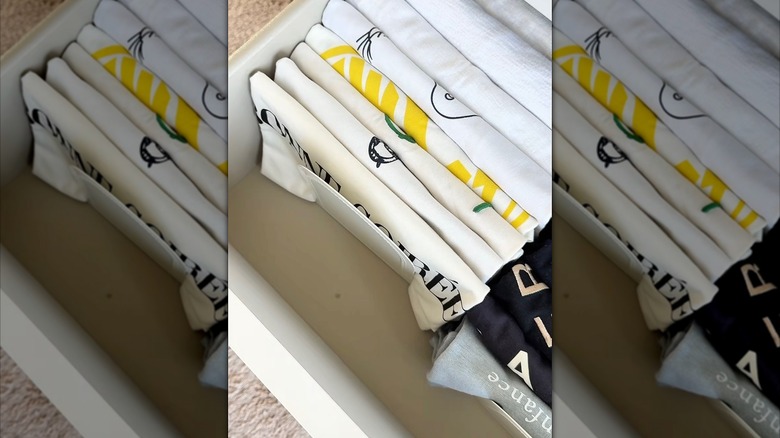 folded shirts lined up in a drawer with a bookend