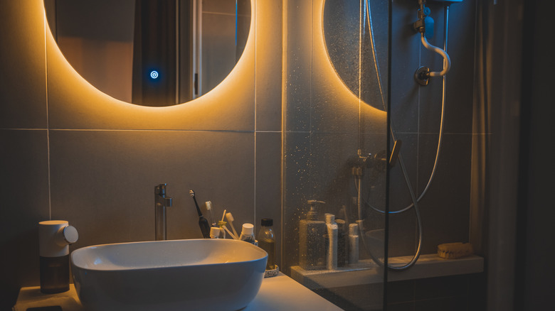 A sleek bathroom with a warm, backlit mirror.