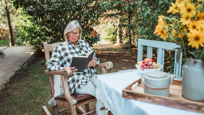 A retired woman relaxing and reading in her garden