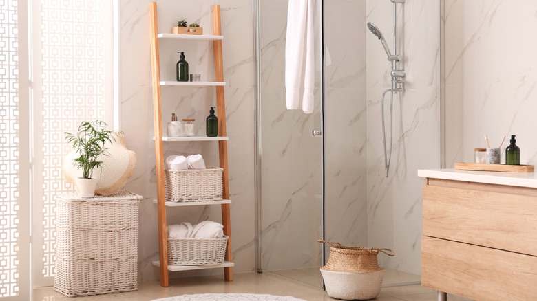 A modern bathroom with white marble slab walls and light wood accents.
