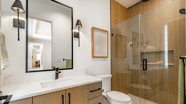 modern bathroom with wood paneled shower walls and vanity with black fittings