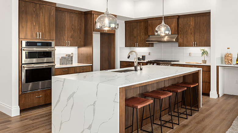 A modern kitchen with a marble counter and wood shelves