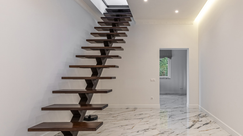 A floating wood staircase and marble floor.