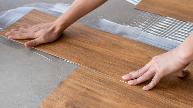 A worker installs luxury vinyl tile planks.