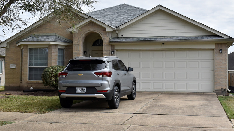 Front of someone's house with a silver car parked on a driveway in need of a makeover.