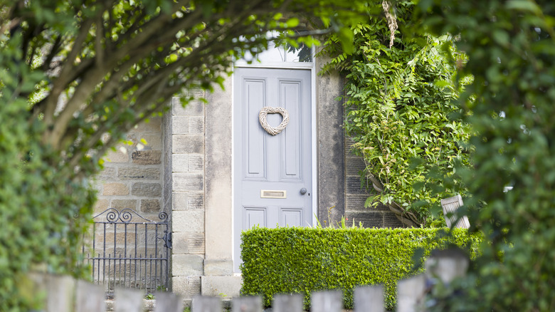 A light blue paneled front door with a heart wreath hanging on it.