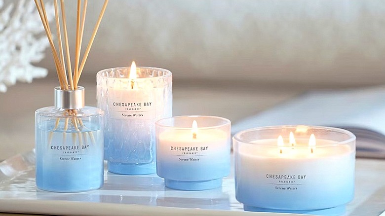 Different sized candles and a diffuser in a tray