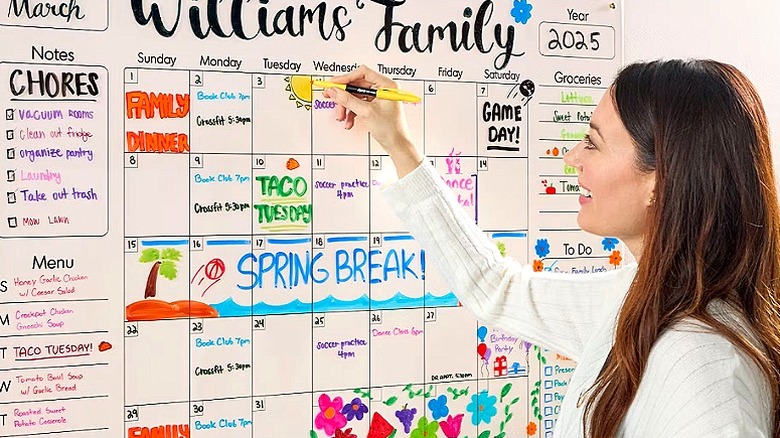 Person uses a yellow marker to draw a sun on a family calendar
