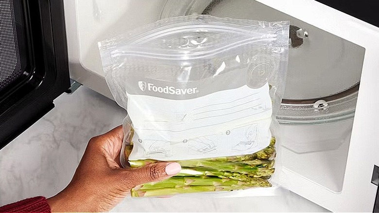Hand holding a food plastic bag in front of an open microwave