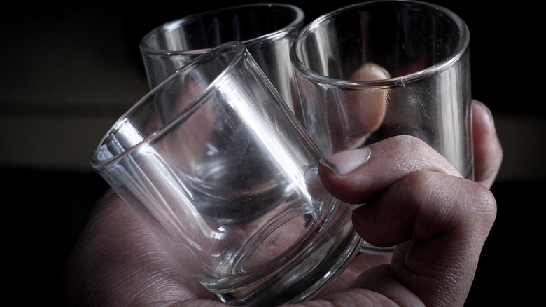Old shot glasses in person's palm