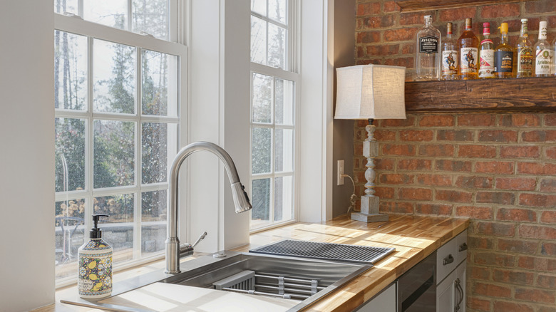 A red accent brick wall in a white kitchen brings warmth and personality to the space.